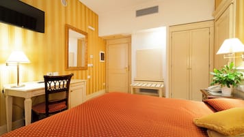 Une chambre d’hôtel équipée d’un lit, d’un bureau, d’une chaise, d’une armoire et d’un téléviseur.