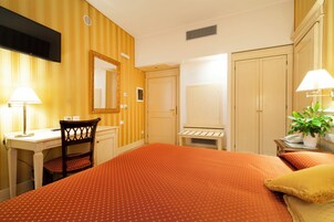 Hotellihuone, jossa on sänky, työpöytä, tuoli, vaatekaappi ja televisio.