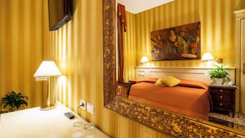 A hotel room with a bed, bedside table, lamp, and a large mirror.