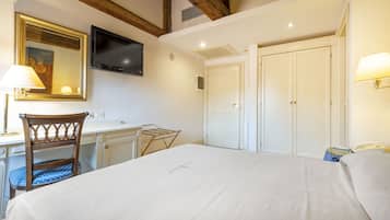 A hotel room with a bed, a desk, a chair, a TV, and a wardrobe.