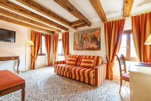 Una stanza accogliente con un divano a righe, travi in legno, un quadro e tende.