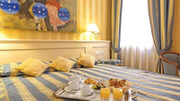 Una habitación de hotel con una cama, una bandeja con alimentos para el desayuno y un cuadro en la pared.