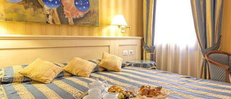 Una habitación de hotel con una cama, una bandeja con alimentos para el desayuno y un cuadro en la pared.