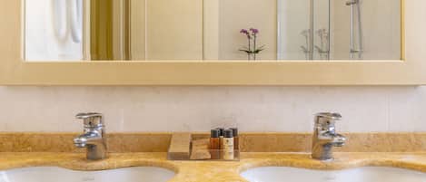 Een badkamer met twee wastafels, een spiegel en een douche.