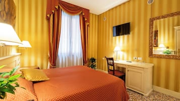 Habitación de hotel con cama, escritorio, silla y un espejo grande.