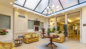 A spacious lobby with a high ceiling, a central round table, and comfortable seating areas. - Hotel Bella Venezia (Venice)