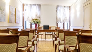 A conference room with a long table, multiple chairs, a laptop, and a vase of flowers. - Hotel Bella Venezia (Venice)