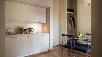 A modern kitchen with white cabinets, a stainless steel sink, and a dining area with a table and chairs.