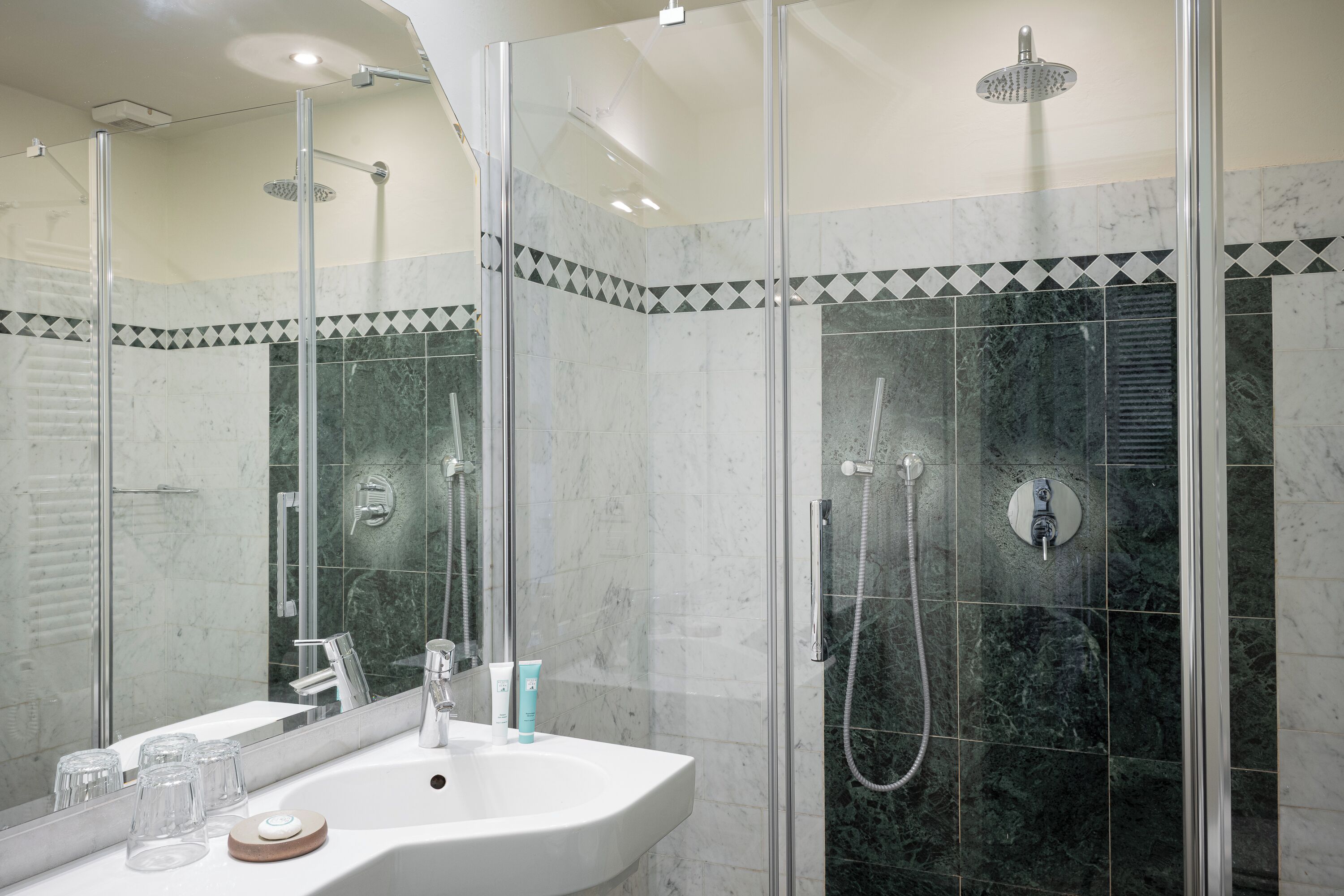 A modern bathroom with a glass-enclosed shower, a white sink, and a mirror.