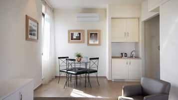 Uma sala moderna com ĂĄrea de jantar, cozinha e sofĂĄ cinza.