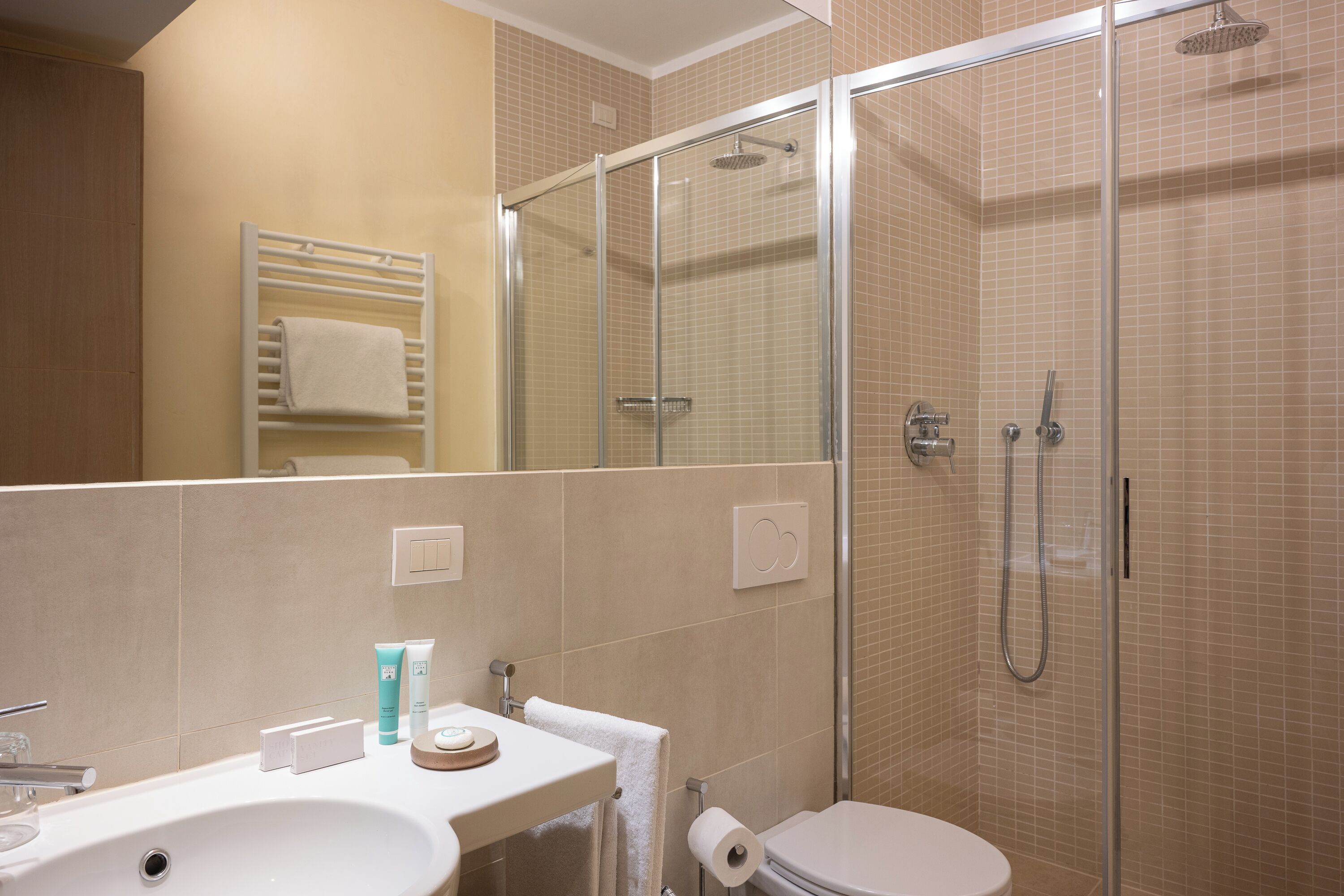Une salle de bain moderne avec une douche à parois de verre, un lavabo blanc et des toilettes.