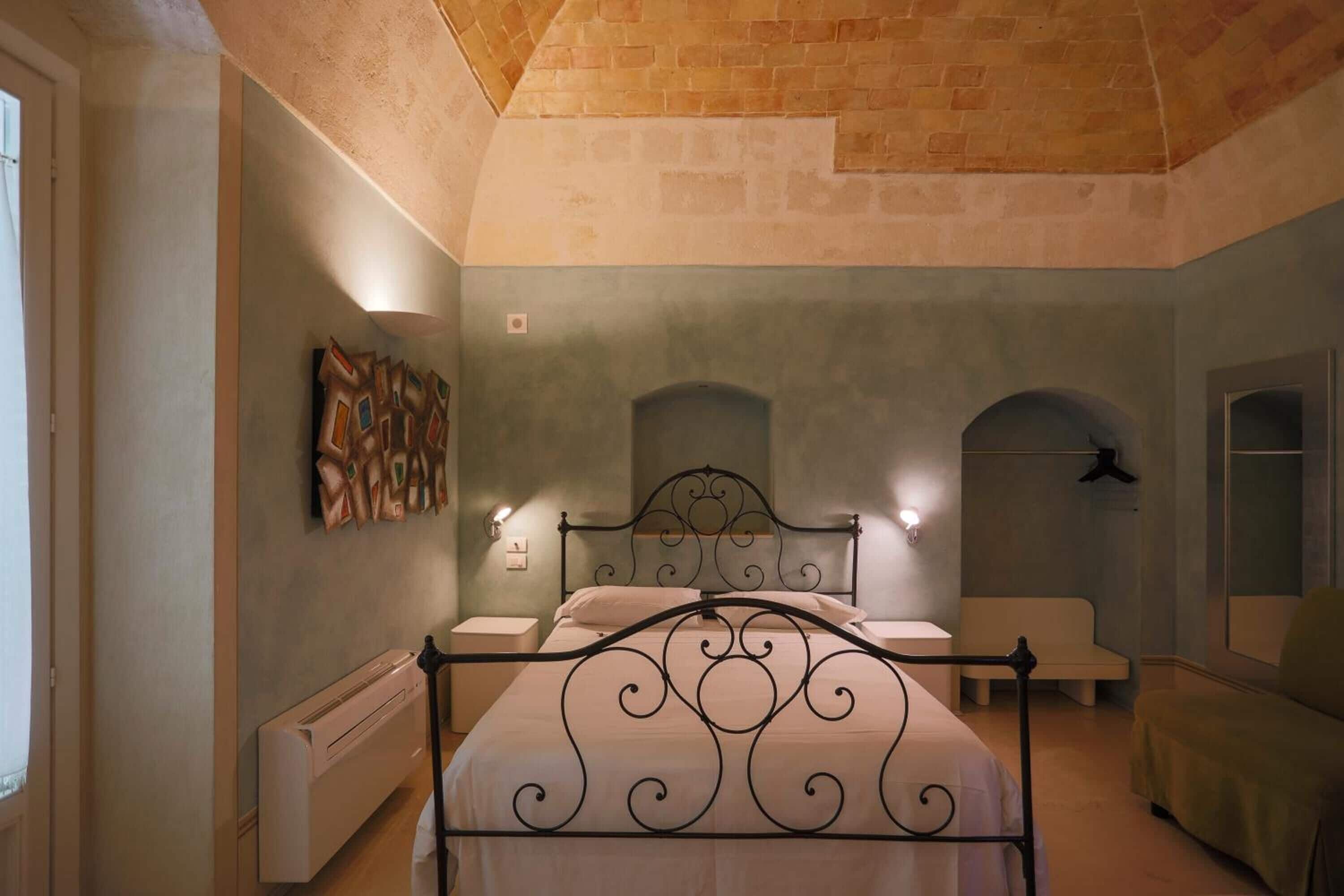 Un dormitorio con cama, mesitas de noche, un radiador y una obra de arte colgada en la pared.