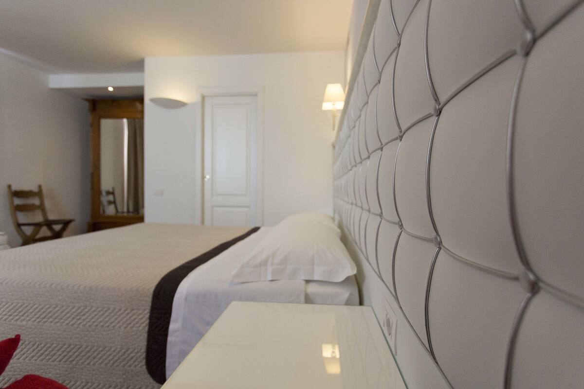 A hotel room with a large bed, a bedside table, and a headboard with a unique design.
