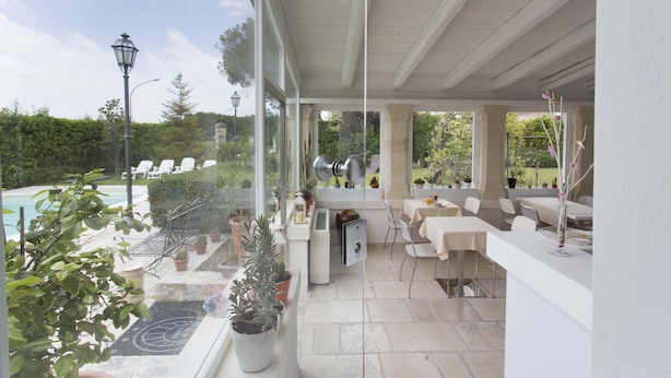 A covered outdoor area with a pool, seating, and potted plants.