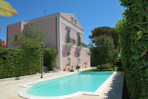 Un edificio a due piani con piscina, immerso nel verde e sotto un cielo sereno.