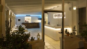An open doorway leading to a reception area with a counter, potted plants, and a visible kitchen in the background.