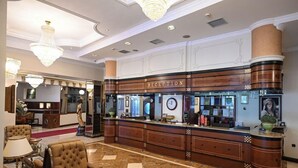 A reception area with a marble floor, a reception desk, and a chandelier. - Stone Bridge Hotel (Skopje)