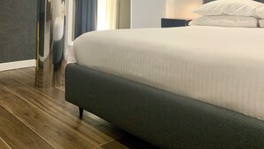 A modern hotel room with a large bed, a unique cylindrical column, and a decorative wall piece.