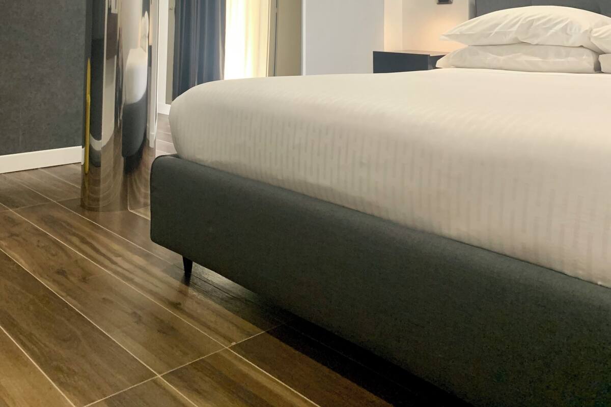 A modern hotel room with a large bed, a unique cylindrical column, and a decorative wall piece.