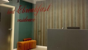 A modern reception area with a reception desk, a seating area with a cushioned bench, and a wall with vertical stripes.