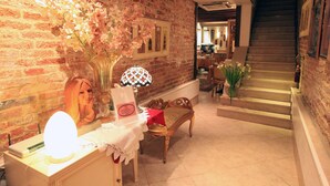 A room with a brick wall, a staircase, a table with a lamp, and a bench. - Residenza Giardini (Venice)
