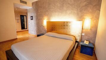 Habitación de hotel con una cama grande, dos lámparas de noche, un teléfono en la mesita de noche y una pequeña mesa.