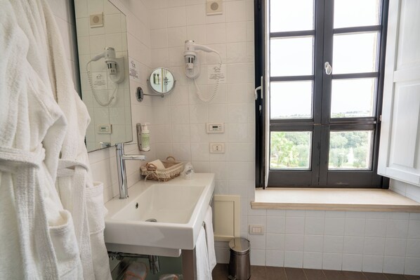 A bathroom with a sink, mirror, towel rack, and a window with a view.