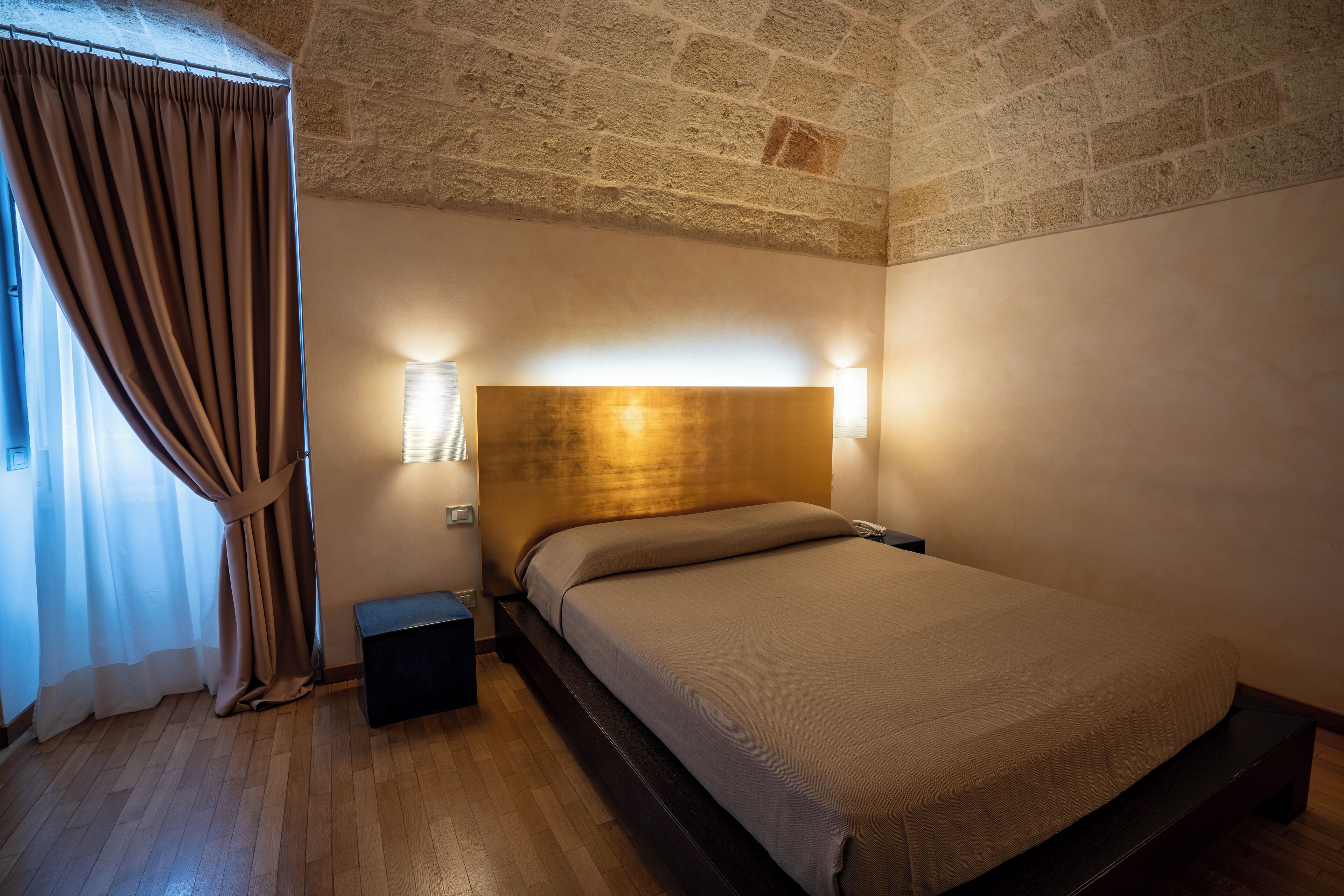 Ein Schlafzimmer mit einem hölzernen Kopfende, einem Nachttisch und einem bei- Bettchen.