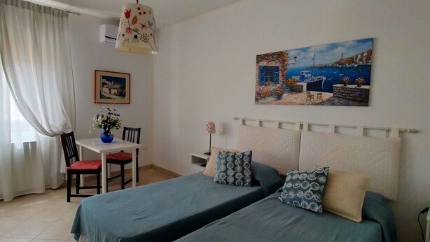 A room with two beds, a desk, a chair, and a painting on the wall. - Sa Chessa (Ploaghe)