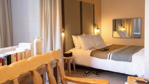 A hotel room with a bed, bedside table, lamp, and a mirror on the wall. - Residence Le Massena (Le Cannet)