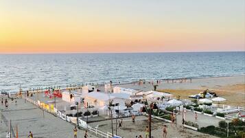 A beachside area with a volleyball court, umbrellas, and beach chairs.