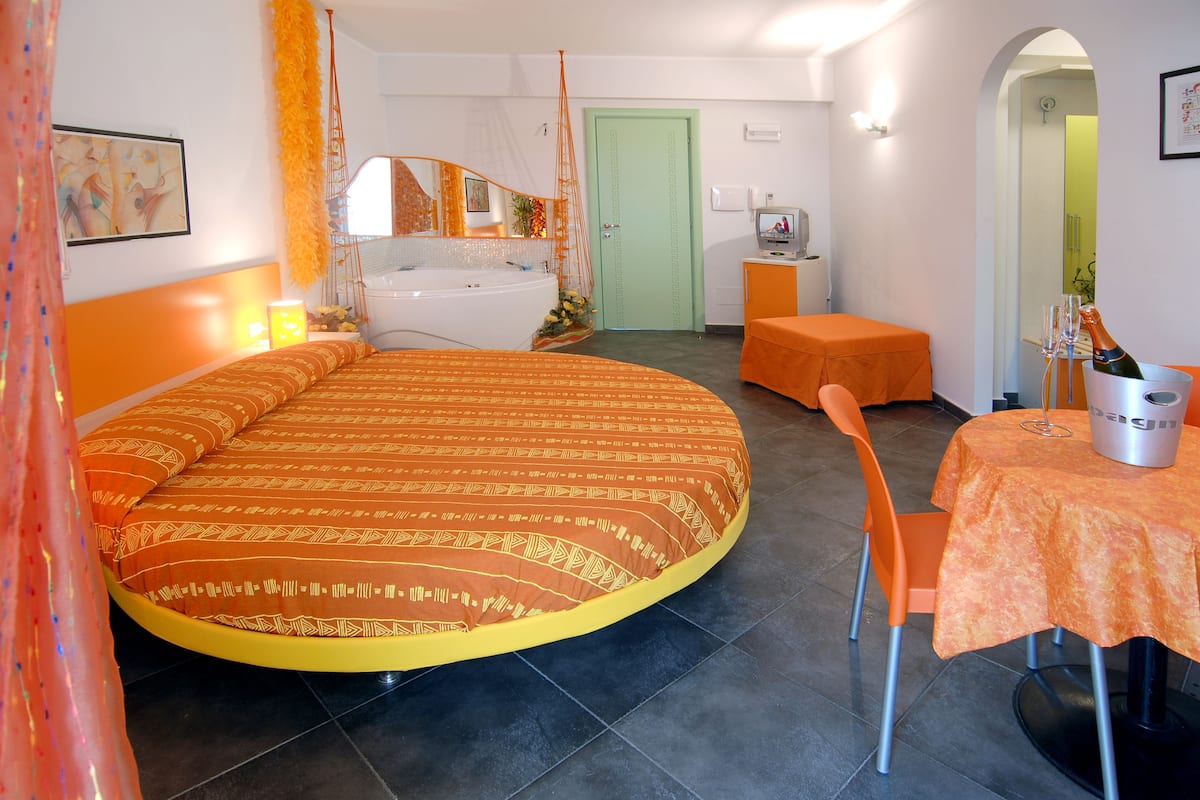 Ein Schlafzimmer mit Bett, einem kleinen Tisch mit Stuhl, einem Badezimmer und einer Tür.