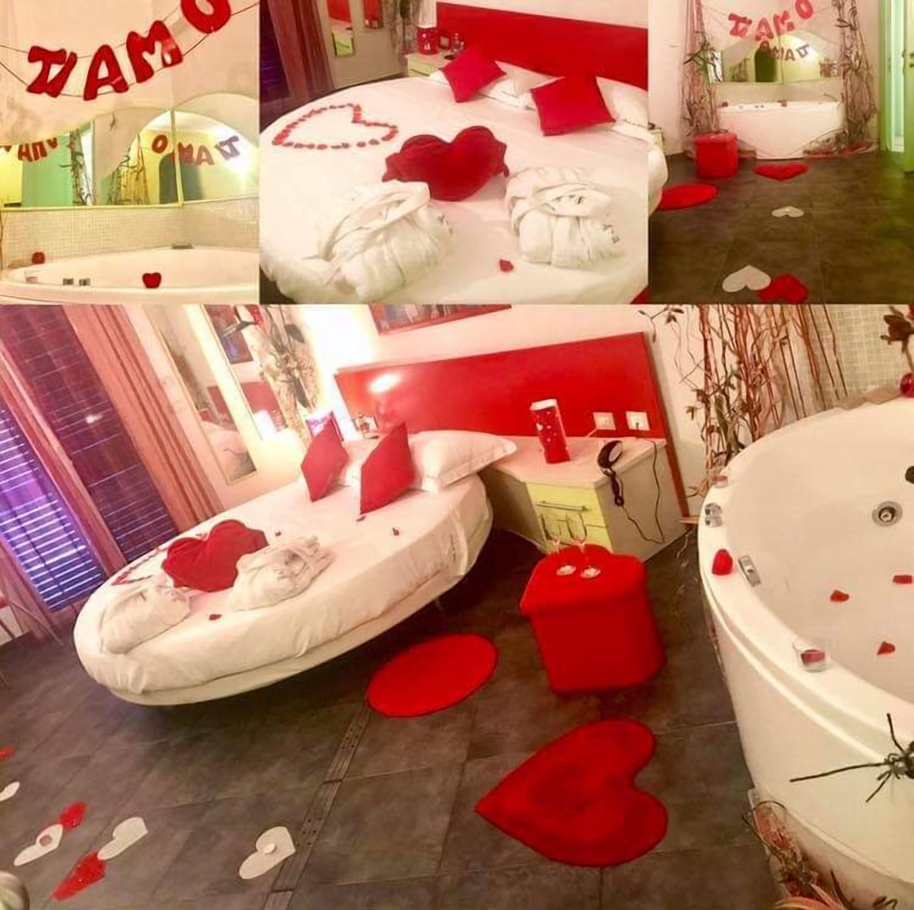 A room with a bed, a red heart-shaped pillow, and a red heart-shaped decoration on the floor.