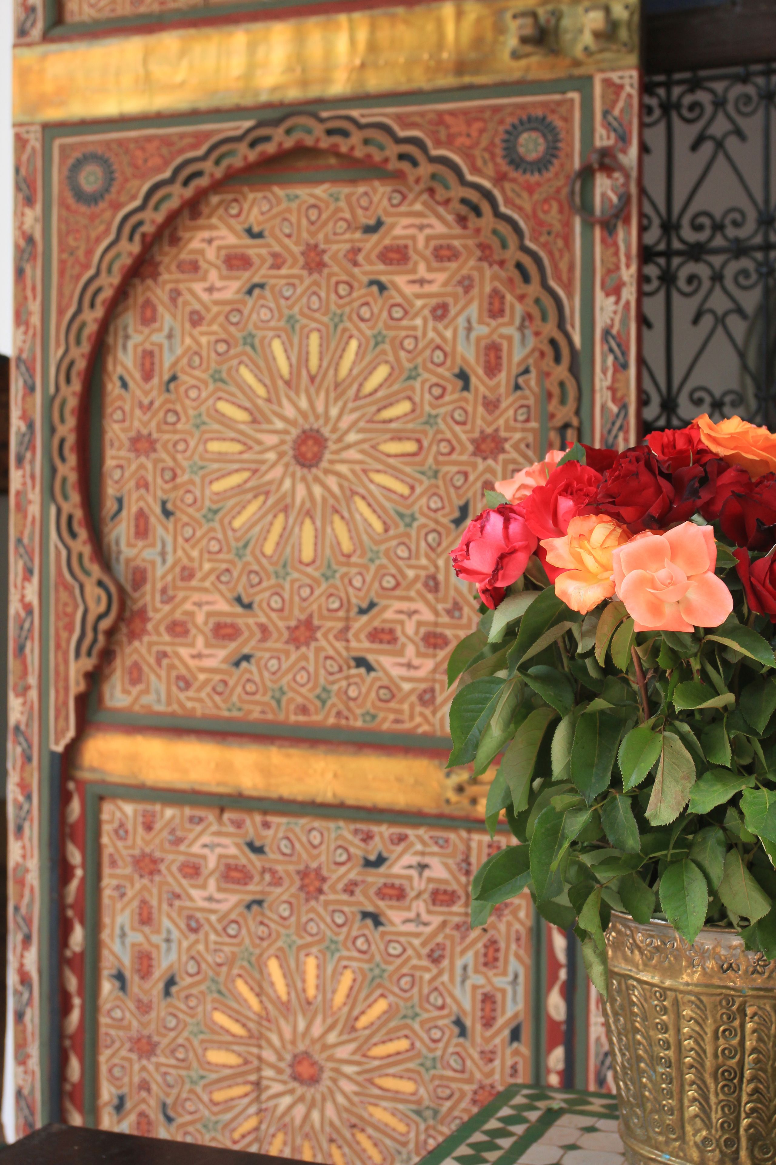Une porte décorative ornée de motifs complexes et un vase rempli de fleurs.