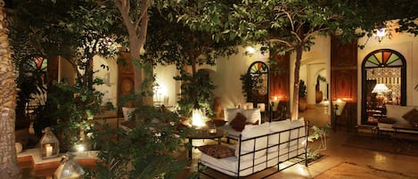 Un jardín interior acogedor con una cama, faroles y un comedor.