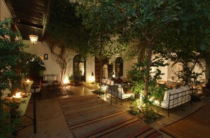 Un patio interior con un sofá, una mesa de comedor y una lámpara.