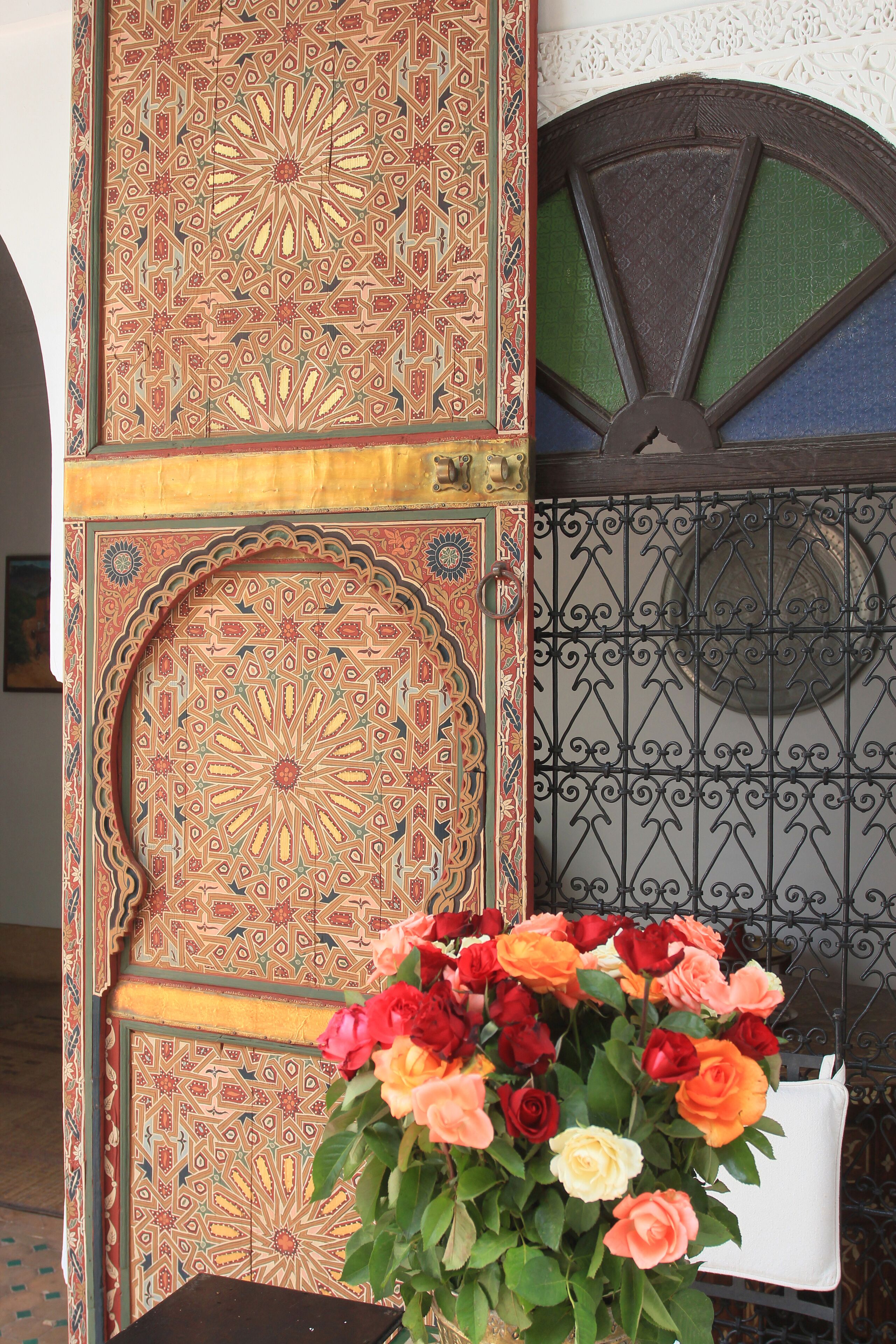 Une porte décorative ornée de motifs complexes et un portail en métal au motif circulaire.