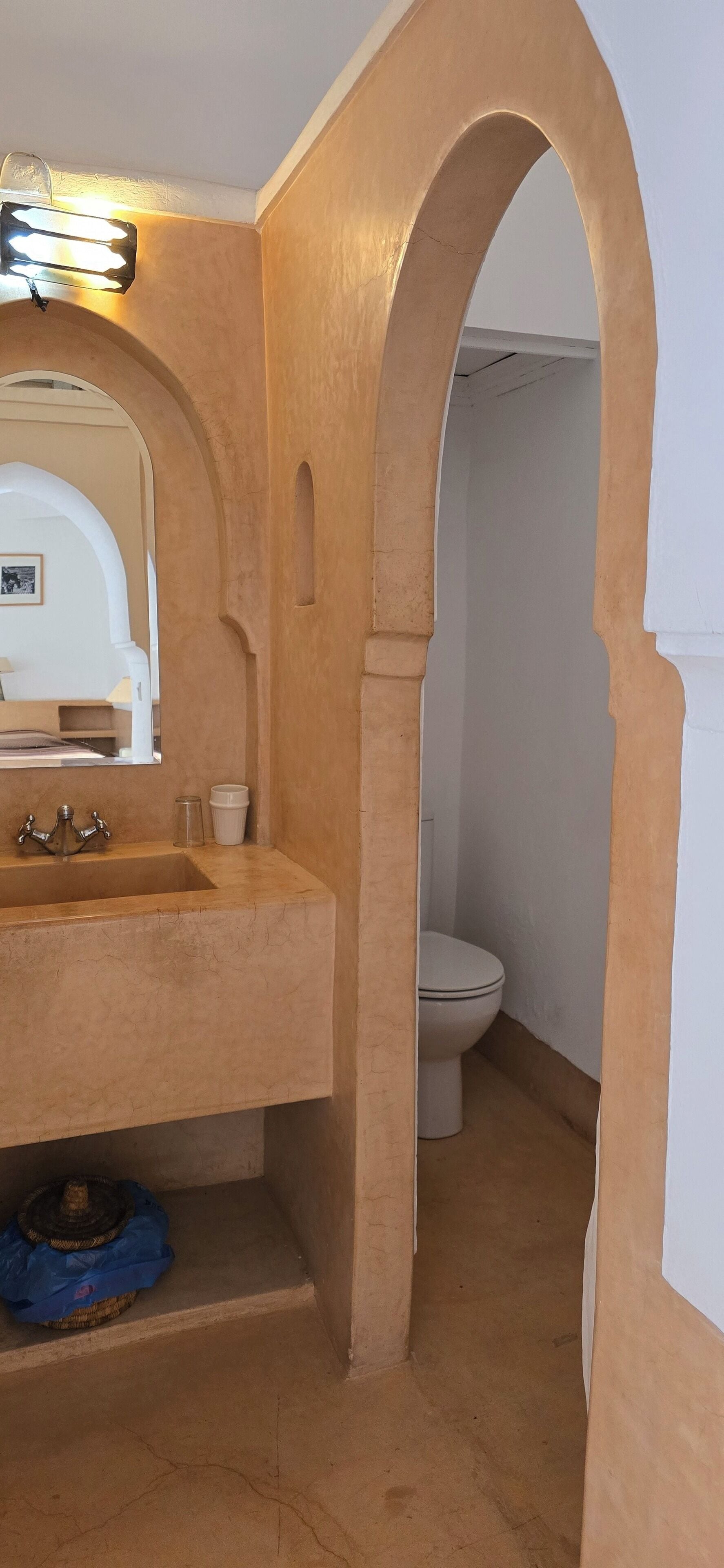 Un baño con un lavamanos color beige, un espejo y un inodoro.