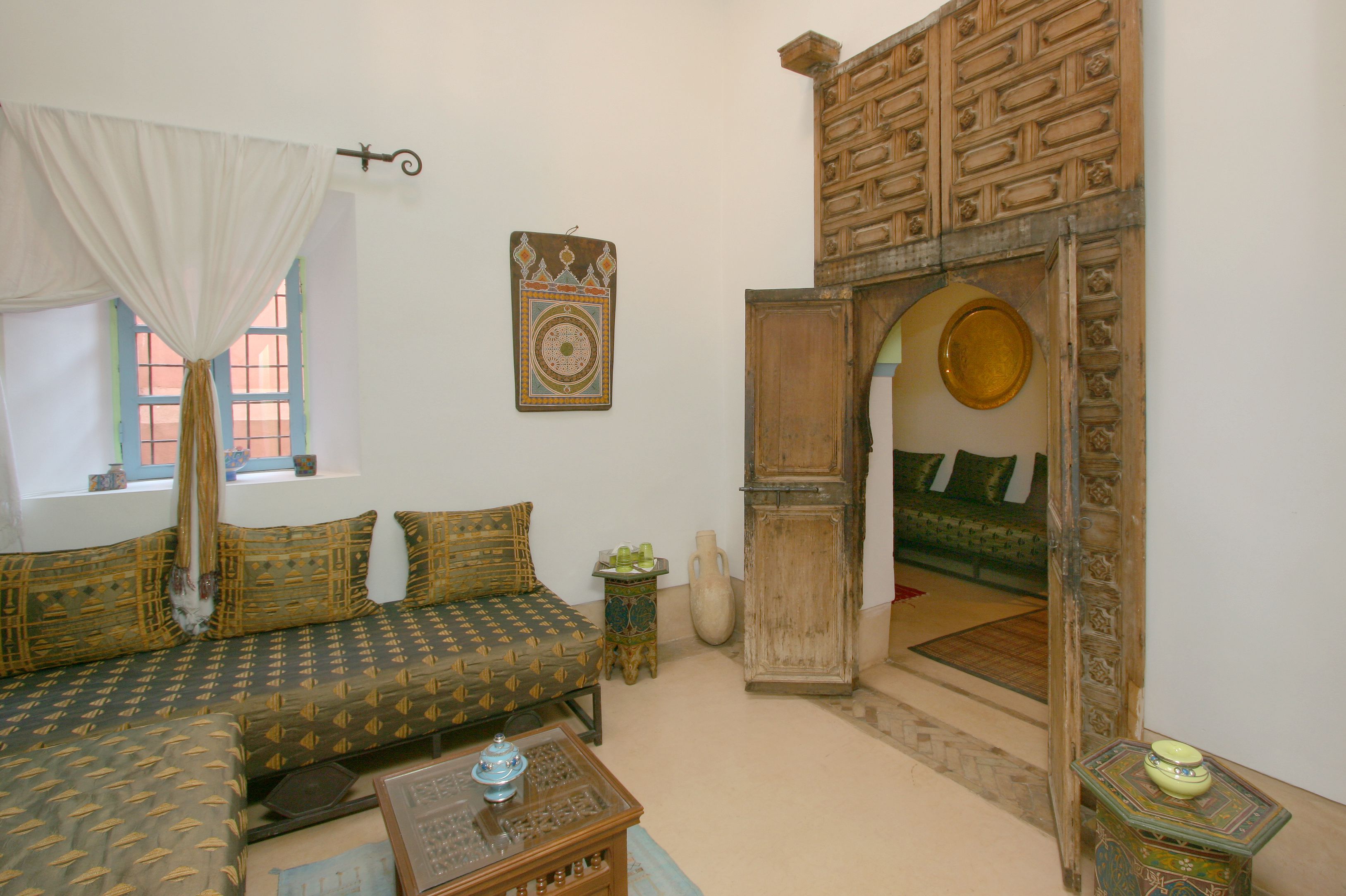 A traditional room with a sofa, a small table, a decorative wall hanging, and a wooden archway.