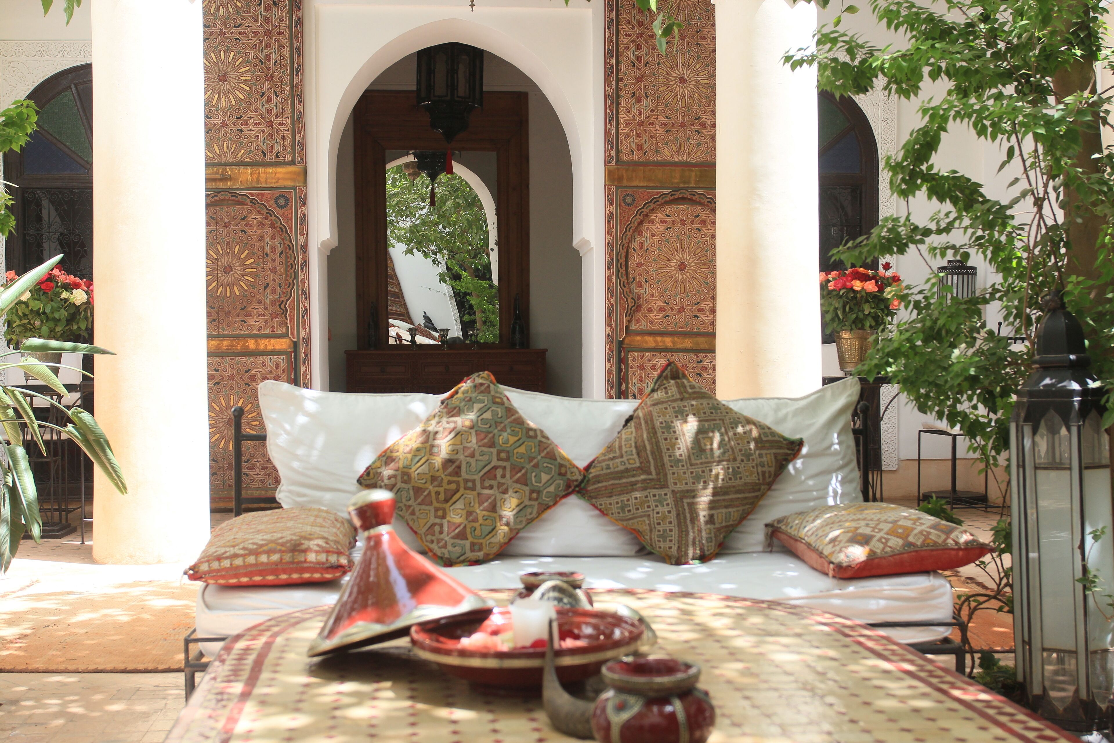 A traditional Moroccan-style room with a sofa set, patterned cushions, and a tray with a teapot and cups.