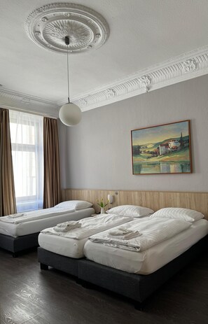 Ein Hotelzimmer mit zwei Betten, einem Bild an der Wand und einer Deckenleuchte.