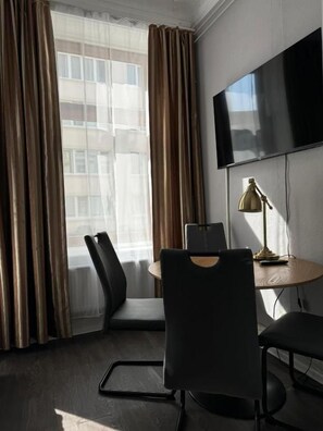 Une chambre d’hôtel équipée d’un téléviseur fixé au mur, d’un bureau avec une lampe et de deux chaises.