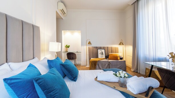 A hotel room with a large bed, a desk, a chair, a small table, and a sofa. - Hotel Catone (Rome)