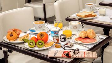 Una mesa de desayuno con pasteles, frutas, café y cruasanes.