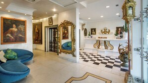 A hotel lobby with a checkered floor, a blue sofa, and a decorative mirror. - Arcom Palace (Pomezia)