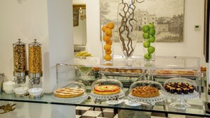 A buffet with various food items, a decorative vase, and a painting on the wall. - Arcom Palace (Pomezia)