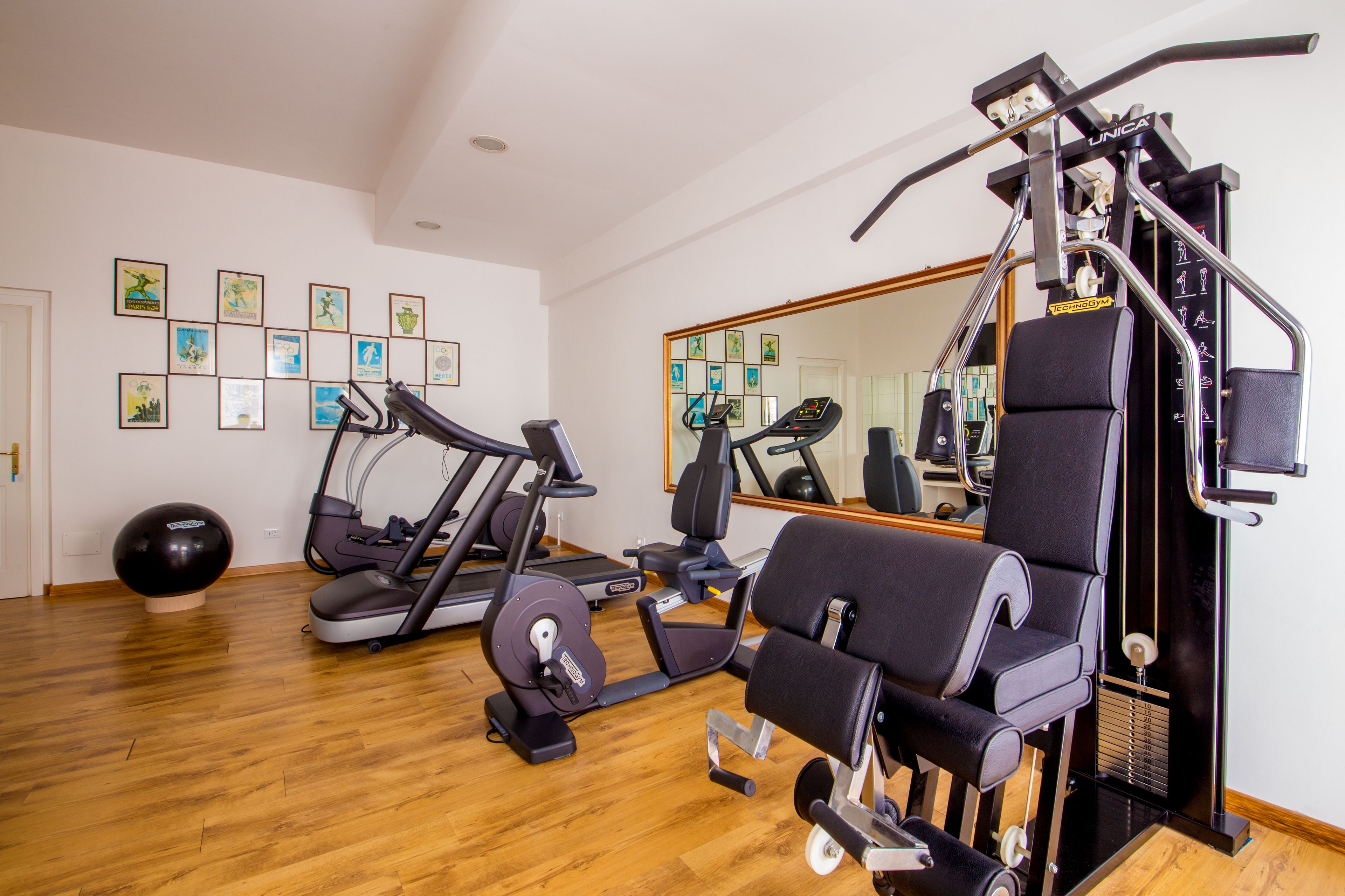 A gym with exercise equipment, a large mirror, and framed pictures on the wall.