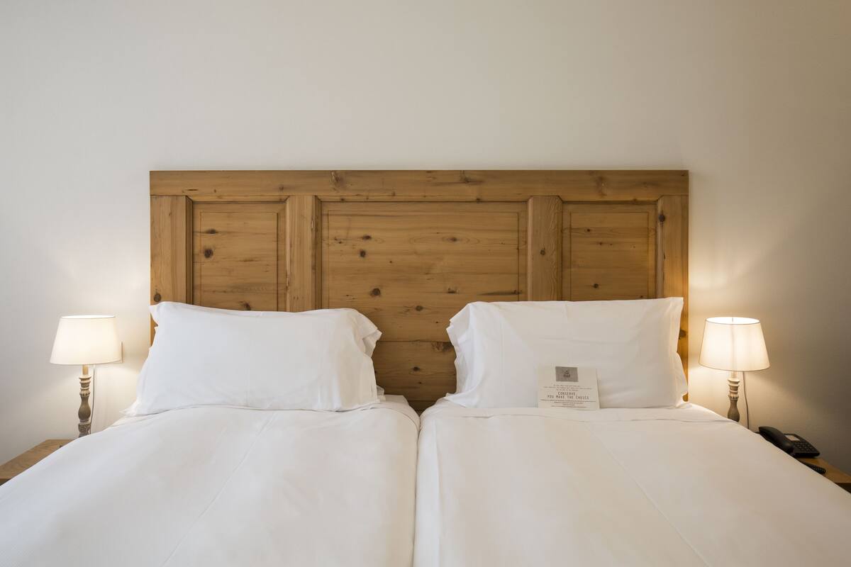 A double bed with a wooden headboard, two bedside lamps, and a bedside phone.