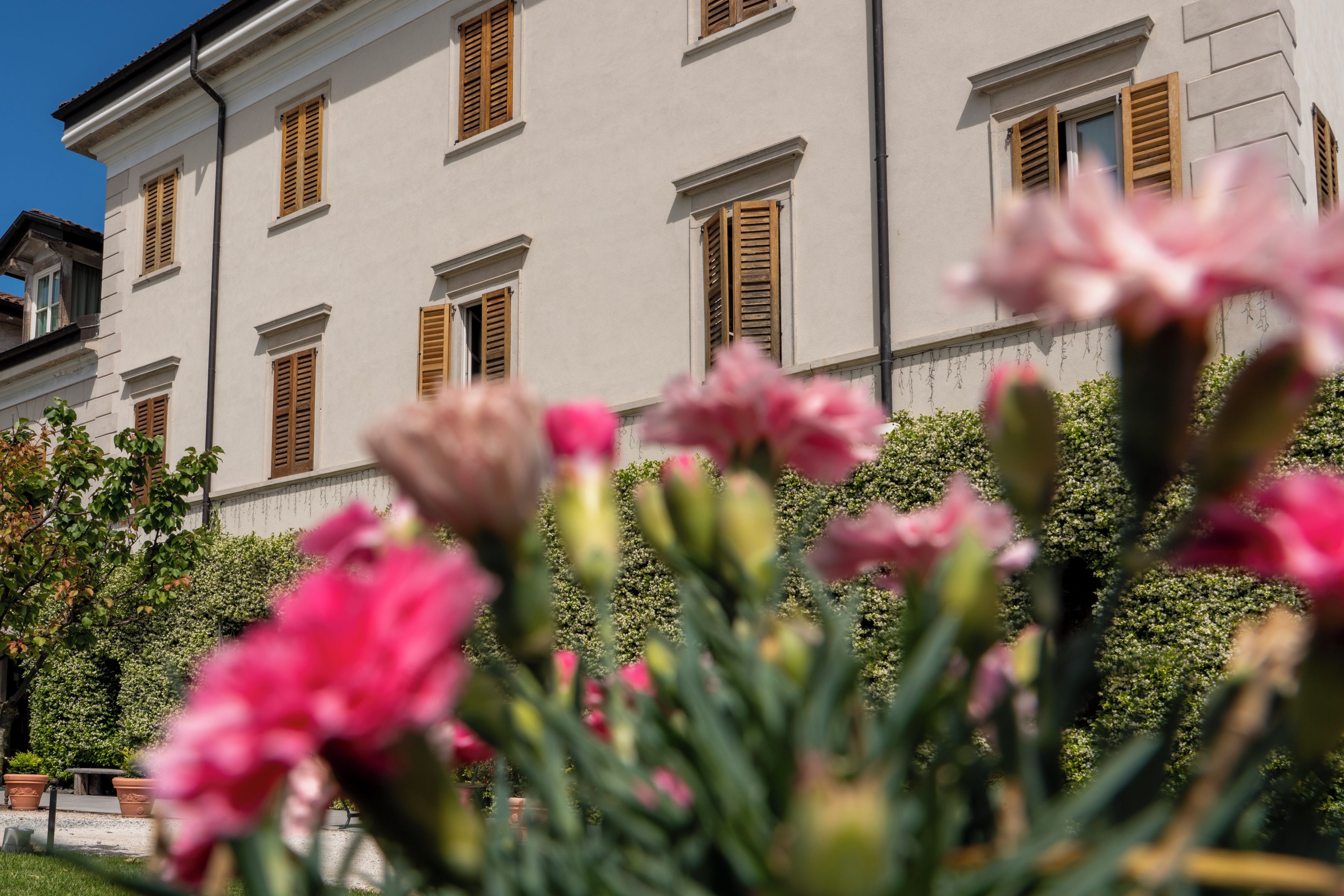 Un edificio con varias ventanas y un jardín con flores rosadas en primer plano.