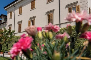 Un edificio con varias ventanas y un jardín con flores rosadas en primer plano.